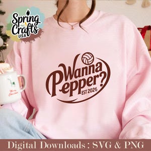 May include: A light pink sweatshirt with the text "Wanna Pepper? EST 2026" in brown. The design includes a volleyball. The image also shows a mug with a reindeer design and the words "Merry Christmas". The sweatshirt is part of a digital download.