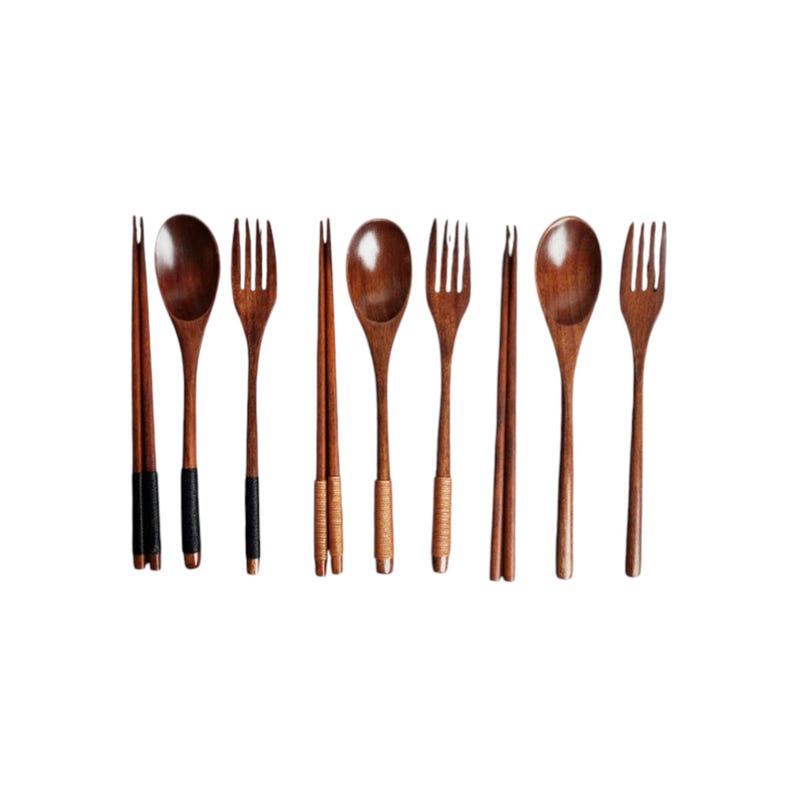 Puede incluir: Un juego de cubiertos de madera, que incluye cucharas, tenedores y palillos. Las cucharas y tenedores son de color marr&oacute;n oscuro, mientras que los palillos tienen detalles en negro o beige. Los utensilios est&aacute;n dispuestos en fila.