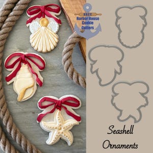 May include: Three seashell-shaped cookies with red ribbon bows, a starfish cookie, and cookie cutter outlines. The cookies are decorated with white icing and gold accents. The text "Seashell Ornaments" is at the bottom.