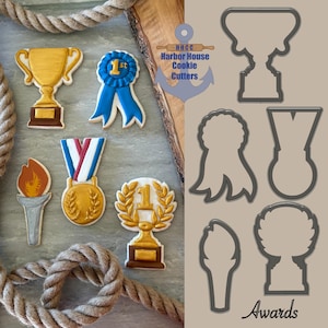 May include: An assortment of award-themed cookies, including a gold trophy, a blue ribbon, and a gold medal. The cookies are decorated with intricate details and sit next to cookie cutter outlines. The image includes the text "Awards".