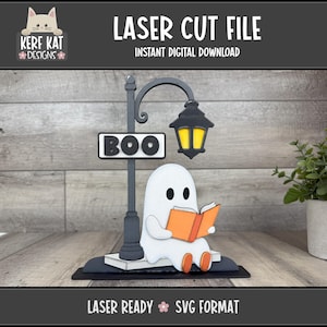 May include: A laser-cut Halloween decoration featuring a ghost reading a book under a street lamp with a "BOO" sign. The lamp has a yellow glow. The design includes the text "LASER CUT FILE" and "SVG FORMAT".