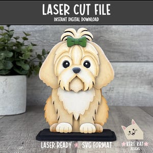 May include: A layered wooden laser cut file of a tan dog with a green bow on its head, featuring large black eyes and a black nose. The design includes the text LASER CUT FILE, INSTANT DIGITAL DOWNLOAD, LASER READY, and SVG FORMAT.