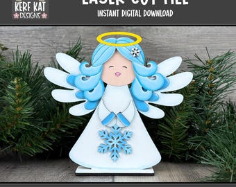 Op de afbeelding: Een lasergesneden engelenbeeldje met blauw haar, vleugels en een halo. De engel houdt een sneeuwvlok vast en staat op een houten voet. De afbeelding bevat de tekst "LASER CUT FILE" en "INSTANT DIGITAL DOWNLOAD".