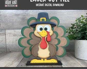 May include: A wooden turkey decoration with a pilgrim hat, green and brown feathers, and a red wattle. The text "LASER CUT FILE" and "INSTANT DIGITAL DOWNLOAD" are displayed at the top. The bottom text reads "LASER READY SVG FORMAT".