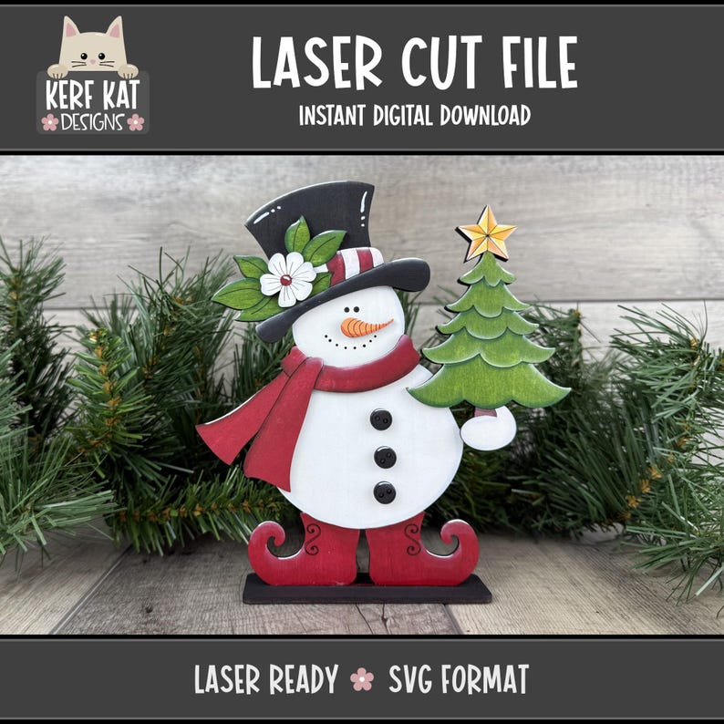 May include: A laser-cut snowman decoration with a black top hat, red scarf, and holding a green Christmas tree. The snowman has a carrot nose, black button eyes, and a smiling mouth. The text "LASER CUT FILE" and "INSTANT DIGITAL DOWNLOAD" are displayed.