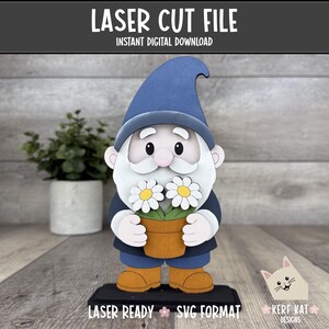 Puede incluir: Un archivo de corte láser de descarga digital que muestra un gnomo con sombrero azul y traje azul oscuro, sosteniendo una maceta marrón con dos margaritas blancas de centro amarillo. El texto LASER CUT FILE, INSTANT DIGITAL DOWNLOAD, LASER READY, SVG FORMAT y KERF KAT DESIGNS es visible.