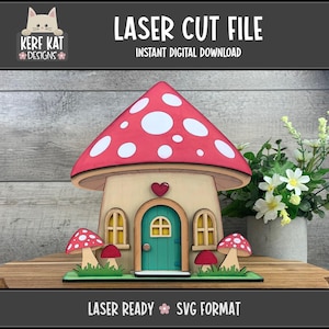 Puede incluir: Una casa de hongos cortada con láser con un techo rojo y blanco con lunares, una puerta turquesa y detalles en forma de corazón. El diseño incluye el texto "LASER CUT FILE" y "INSTANT DIGITAL DOWNLOAD".