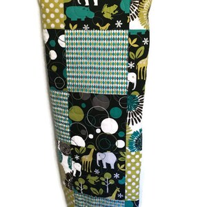 May include: A patchwork quilt with a black background and various animal prints, including elephants, giraffes, and hippos. The quilt is made of different fabrics with geometric patterns in shades of green, blue, and white.