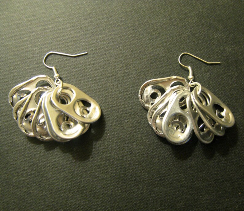 May include: A pair of handmade silver earrings. Each earring features a cluster of recycled aluminum can pull tabs, suspended from a silver hook. The earrings have a unique, upcycled aesthetic.
