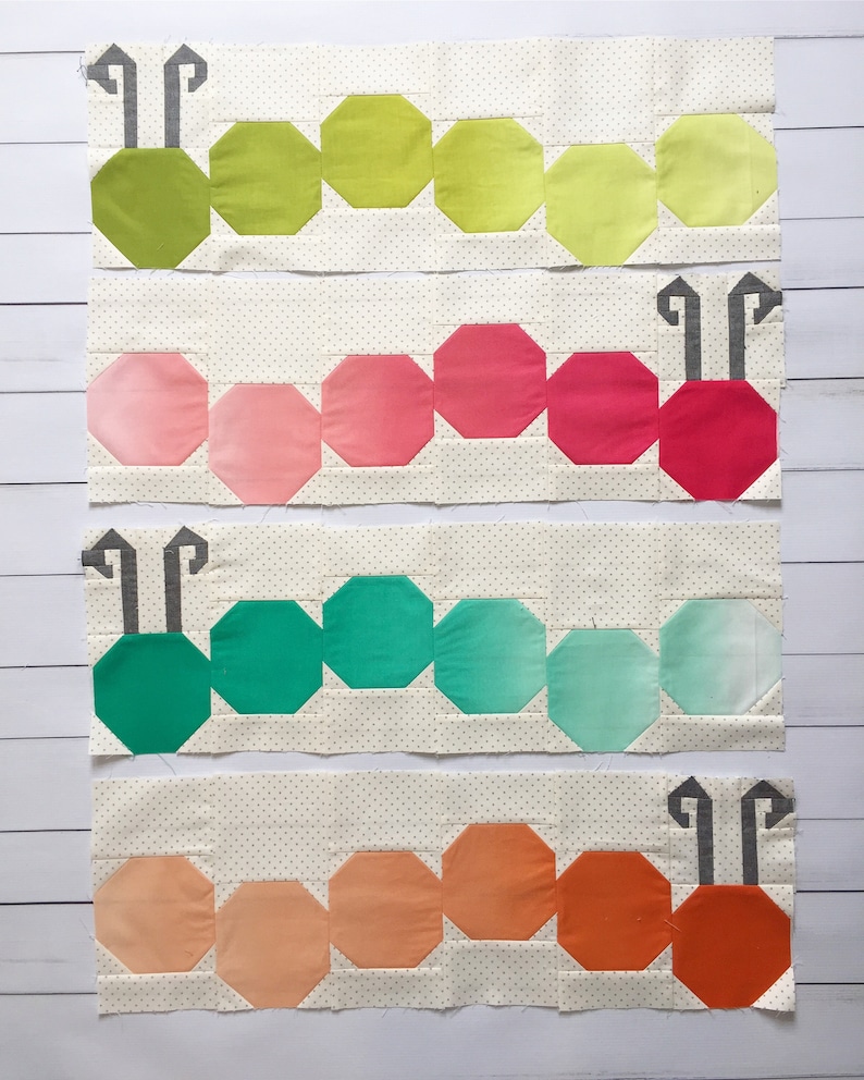 Op de afbeelding: Vier rijen van stoffen patchwork die aan elkaar zijn genaaid om een ​​rupsontwerp te cre&euml;ren. De rups is gemaakt van verschillende tinten groen, roze, turquoise en oranje stof. Elke rij heeft een ander kleurenschema.