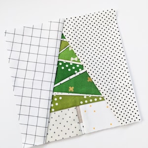 May include: A patchwork Christmas tree design made from various fabrics. The tree is constructed from shades of green fabric with polka dots and other patterns. A white fabric with a black grid pattern and a white fabric with black polka dots partially cover the design.