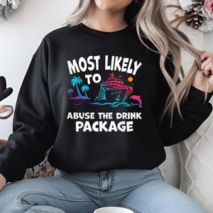 May include: Black sweatshirt with white text that reads "Most Likely To Abuse The Drink Package". The text is surrounded by a colorful graphic of a cruise ship, palm trees, and a dolphin.