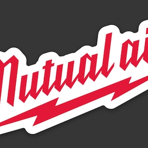 May include: A white sticker with the words "Mutual aid" in red, stylized gothic lettering. A red lightning bolt underlines the text, set against a dark gray background.
