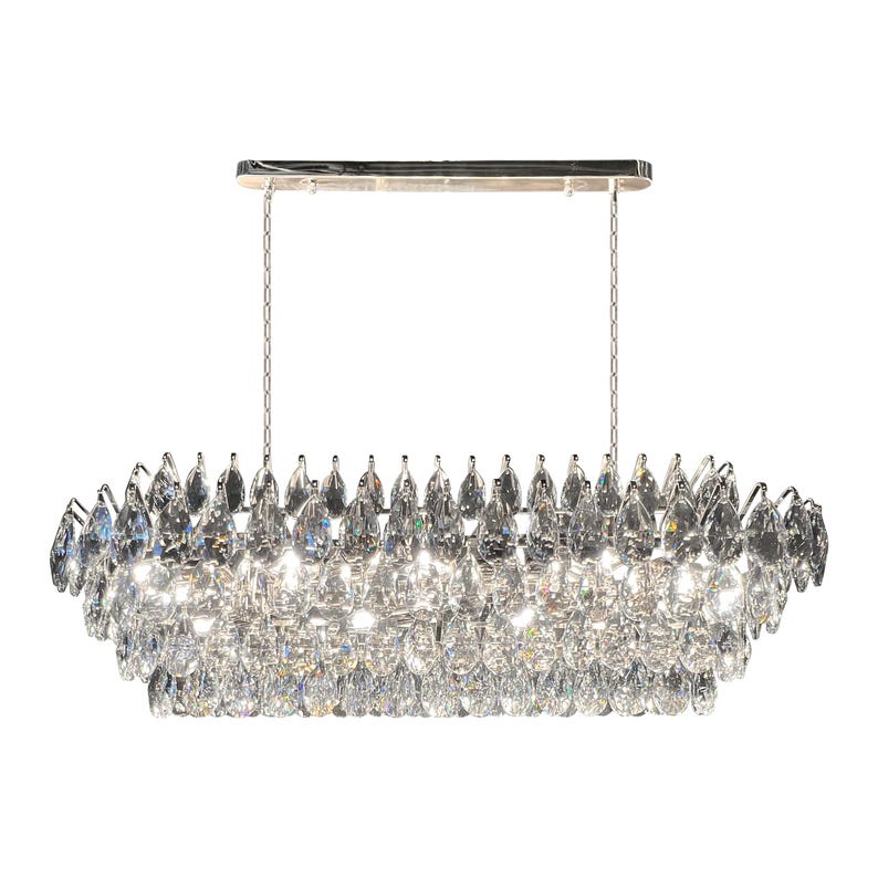 May include: A rectangular chandelier with a polished chrome finish. The fixture is adorned with numerous clear crystal teardrop-shaped pendants, suspended from a chrome frame by delicate chains. The crystals reflect light, creating a sparkling effect.