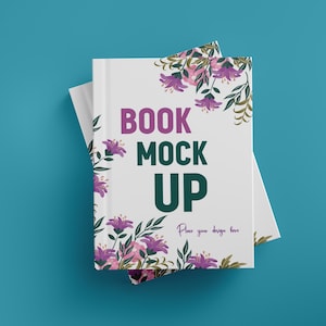 May include: A white book mockup with the text "BOOK MOCK UP" in purple and green. The book is decorated with purple flowers and green leaves. The words "Place your design here" are also visible.