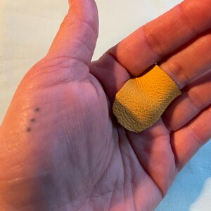 May include: A small piece of yellow leather with a rough texture.