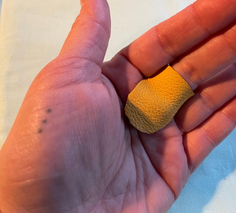 May include: A small piece of yellow leather with a rough texture.