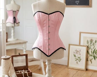Corsé rosa de satén sobre el busto / Ribete negro, cinturilla con cordones, estilo victoriano