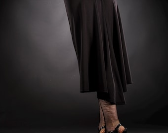 May include: A black skirt with a gathered waistline and a flowing hemline. The skirt is paired with black fishnet stockings and black high-heeled shoes.