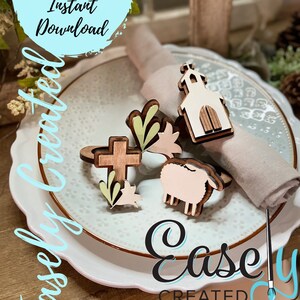 May include: Wooden Easter-themed napkin rings on a white plate. The set includes a cross, a church, a lamb, and floral accents. The image also includes the text "Digital Cut File Instant Download" and "Easely Created".