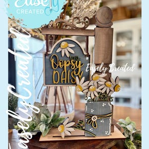 Puede incluir: Un letrero decorativo de madera con el texto "Oopsy Daisy" y detalles de margaritas. El letrero es parte de una mini exhibición de poste. La imagen también incluye un jarrón con flores y el texto "Easely Created" y "Instant Digital Download".