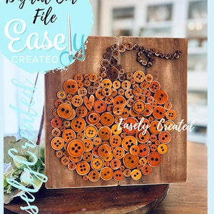 May include: A wooden pumpkin decoration made of various orange and brown buttons. The pumpkin is mounted on a wooden board. The text "Digital Cut File Easely Created" is visible in the image.