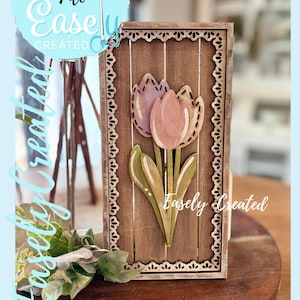 Può includere: Cartello in legno con due tulipani rosa e verdi su uno sfondo rustico a venature di legno. Il cartello è incorniciato con un bordo decorativo e include il testo "Easely Created" e "Digital Cut File".