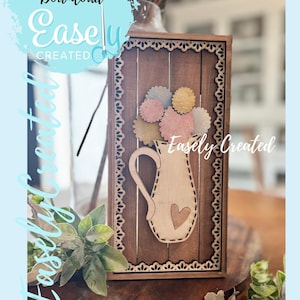 May include: Wooden wall art featuring a vase with flowers. The vase is light-colored with a heart, and the flowers are pastel shades. The frame is brown with a decorative border. Text on the image says "Instant Digital Download Easely Created."