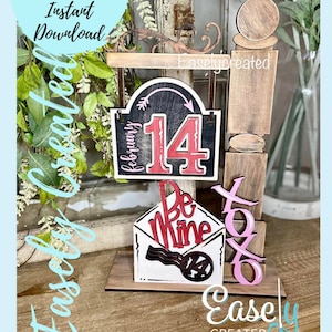 May include: A wooden Valentine's Day display with a black and red sign reading "14 February" and an arrow. An envelope with "Be Mine" and "XOXO" letters is below. The words "Digital Cut File Instant Download" are also visible.