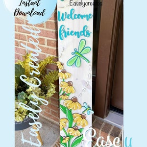 May include: A wooden sign with the words "Welcome friends" painted in blue. The sign is decorated with yellow flowers, green leaves, and blue dragonflies. The sign is leaning against a brick wall.
