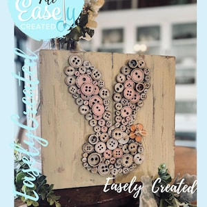 May include: A wooden bunny decoration made from various buttons in shades of pink, white, and brown. The bunny is on a distressed wooden block. The text "Easely Created" and "Digital Cut File" are visible.