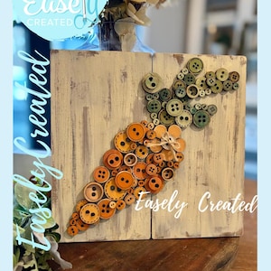 May include: A wooden plaque featuring a carrot design made of various sizes and shades of orange and green buttons. The plaque has a distressed, light-colored background with the text "Easely Created" in a cursive font.