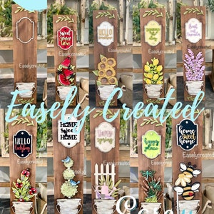 Könnte beinhalten: Eine Sammlung von Holzschildern mit verschiedenen Designs, darunter Blumenarrangements, saisonale Themen und Willkommensbotschaften. Jedes Schild hat einen dekorativen Eimer und eignet sich für die Heimdekoration.