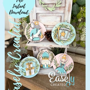 Könnte beinhalten: Fünf hölzerne Weihnachtsornamente mit einem Nussknacker, einer Ballerina, einem MauseSoldaten, einer Trommel und Geschenken. Die Ornamente sind in Blautönen, Rosa und Grün bemalt. Die Ornamente befinden sich auf einem Holzregal mit einem Schild, auf dem "Easley Created" steht.