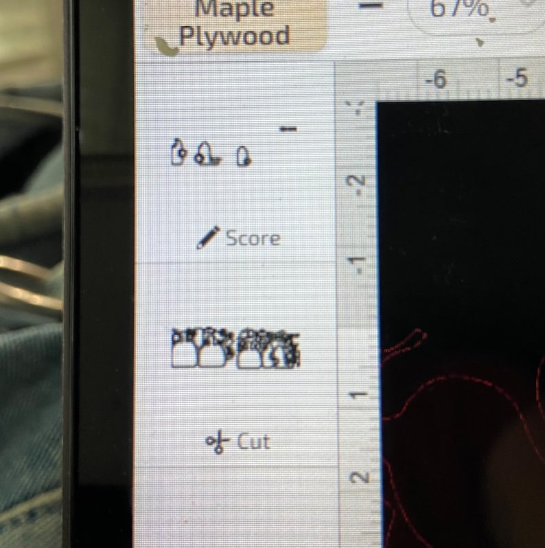 以下が含まれることがあります： コンピューター画面に、歯の列の白黒画像が表示されたデザインソフトウェアのインターフェースが表示されています。ソフトウェアには、「スコア」と「カット」のオプションと、インチ単位の目盛りが付いた定規があります。画面の上部には、「メープル合板」と「67％」のテキストが表示されています。