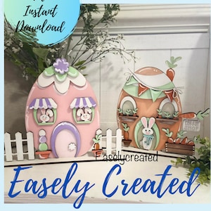 May include: Two wooden Easter egg houses, one pink with bunny windows and a purple door, the other brown with green trim and a carrot shop sign. Both are decorated with flowers and carrots. The houses are on a white picket fence and a white surface with the text "Easly Created" in blue.