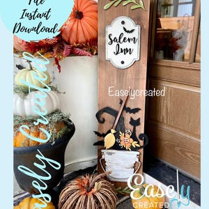 Puede incluir: Un letrero de madera con un sombrero de bruja, una escoba y un gato, junto con un cubo y un letrero que dice "Salem Inn". El letrero está decorado con follaje de otoño y calabazas.