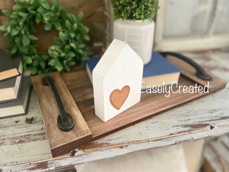 May include: A wooden tray with a black metal handle. The tray is decorated with a white wooden house with a brown heart cutout. The text "EaselyCreated" is visible on the tray.