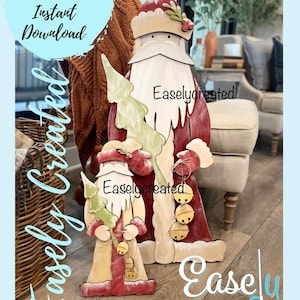 Può includere: Un file di taglio digitale per un progetto di artigianato natalizio con un Babbo Natale grande e un Babbo Natale più piccolo che tiene un albero di Natale. Le figure di Babbo Natale sono dipinte in rosso, bianco e verde con un aspetto rustico e invecchiato. Il testo "Easlycreated" appare sull'immagine.