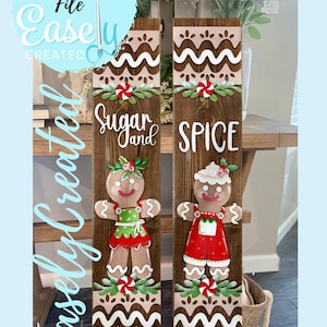 May include: Two wooden signs with gingerbread people. One sign says "Sugar and Spice" with a gingerbread person wearing a green dress. The other sign says "Spice" with a gingerbread person wearing red overalls. The signs have a light brown background.