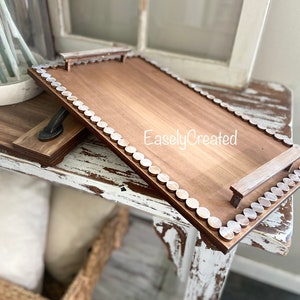 May include: A rectangular wooden tray with a brown stain and white painted edges. The tray has two wooden handles and a white bead border. The text "EaslyCreated" is printed on the tray.