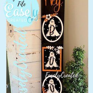 Puede incluir: Un letrero de madera negro de Halloween con la palabra "Hey" en escritura naranja. El letrero presenta tres diseños de fantasmas con el texto "Easely Created" y "Digital Cut File". Cada fantasma está decorado con follaje otoñal.