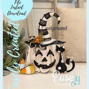 Pode incluir: Uma abóbora branca com um chapéu de bruxa preto e branco, um gato preto e milho doce. A abóbora tem um rosto de abóbora esculpido. O texto "Easlycreated" está no chapéu e o texto "Easly CREATED" está na parte inferior direita da imagem.