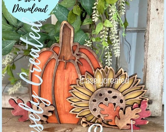 May include: Wooden fall-themed decoration featuring a pumpkin, sunflower, and leaves. The pumpkin is orange with a brown stem, the sunflower has yellow petals, and the leaves are red and brown. Text on the image says "Digital Cut File Instant Download" and "Easely Created".