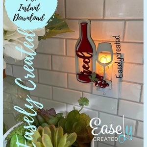 May include: A red wine bottle and glass nightlight plug-in. The wine bottle has the word "Wine" written on it. The nightlight is plugged into a white outlet on a white tiled wall. The text "Easley Created" is visible in the lower right corner of the image.