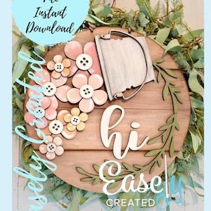 May include: Wooden round sign with floral and leaf accents. The sign features the words "Hi Ease" and "Created" in white script. Pink and yellow flowers with button centers are on the left side. The text "Digital Cut File Instant Download" is in a blue circle.