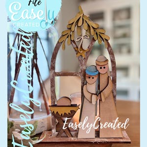 May include: Wooden nativity scene with a star and arch design. The figures of Mary, Joseph, and baby Jesus are depicted in a rustic style. The text "Easely Created" and "Digital Cut File" are visible.