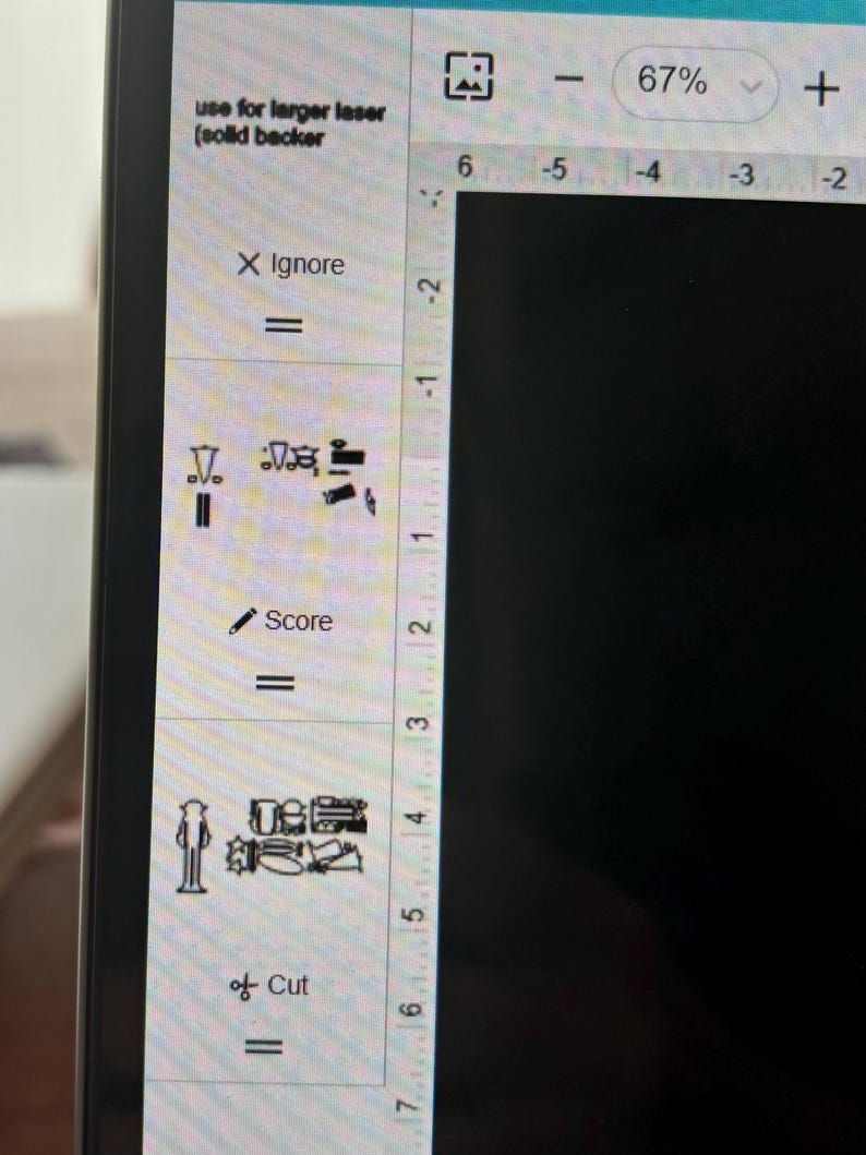 May include: A computer screen displaying a design program with a zoom level of 67%. The program has a menu on the left side with options to ignore, score, and cut. The design area is black and empty.