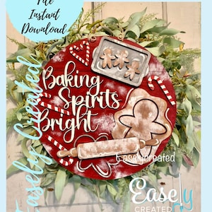 May include: A red wooden round sign with the text "Baking Spirits Bright" in white lettering. The sign is decorated with a gingerbread man cookie cutter, a rolling pin, candy canes, and a baking pan with three gingerbread men cookie cutters. The sign is surrounded by a green leafy wreath.