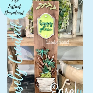 Puede incluir: Un letrero de madera con las palabras "Happy Place" sobre un fondo verde. El letrero está decorado con libélulas verdes y una planta en maceta. El letrero está hecho para manualidades y es un archivo de corte digital.